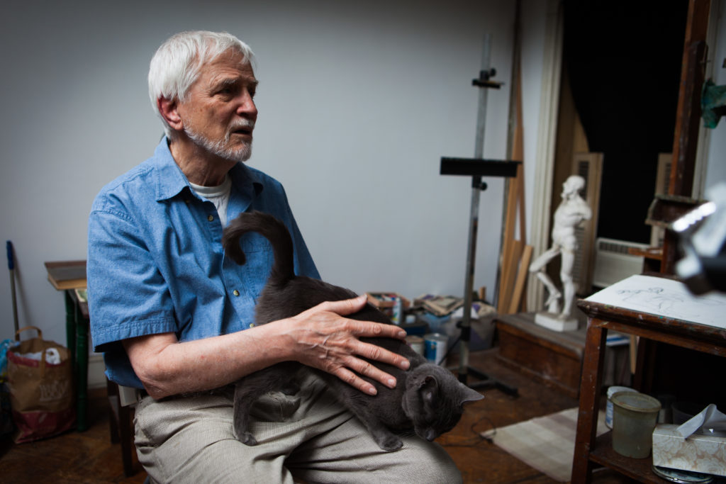 Lennart Anderson sitting in a chair in his studio with gray cat on his lap