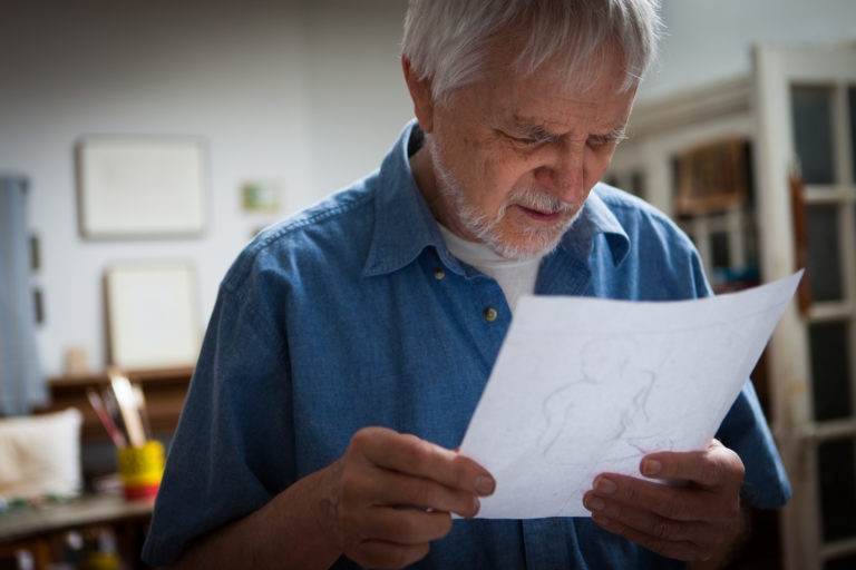 Lennart Anderson in his studio looking at a drawing that he his holding in his hands