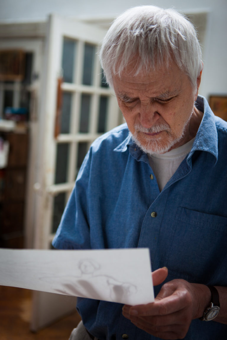 Lennart Anderson in his studio looking down at a figure drawing that he is holding in his hands