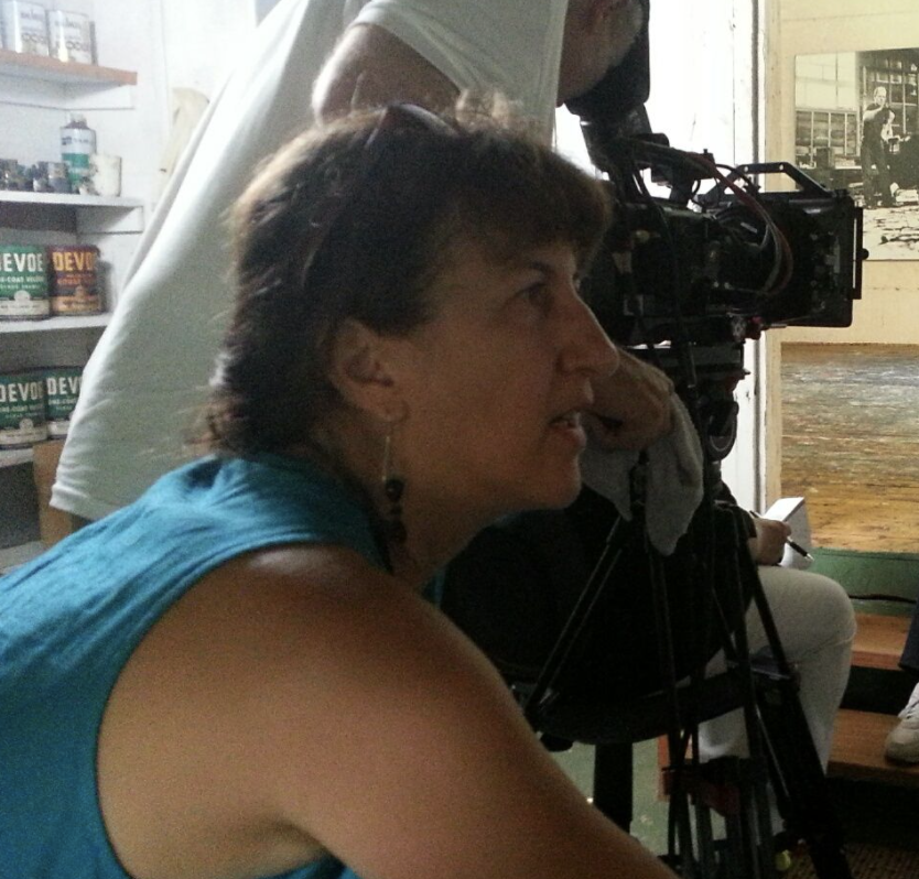 profile color photograph of filmmaker Andrea Torrice in blue sleeveless shirt lit from behind
