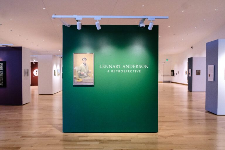 Closeup: front display wall of the Lennart Anderson exhibition. Front lit green wall with a painting of a man and the exhibition title.